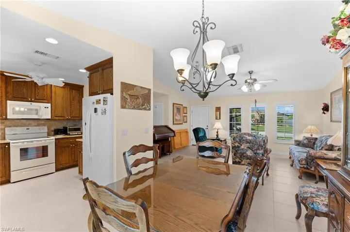 Dining area featuring light tile flooring and ceiling fan with notable chandelier