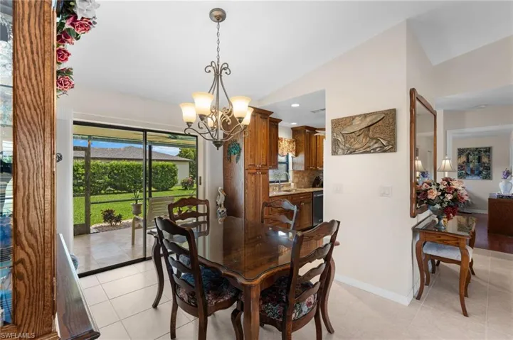 Tiled dining space with a notable chandelier, sink, and lofted ceiling