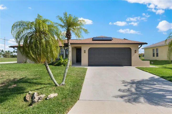 Single story home featuring a garage, a front lawn, and solar panels