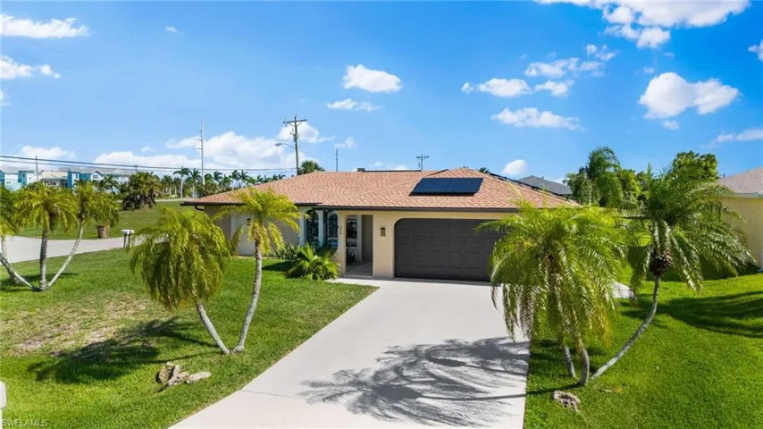 View of front of house with a front lawn, a garage, and solar panels
