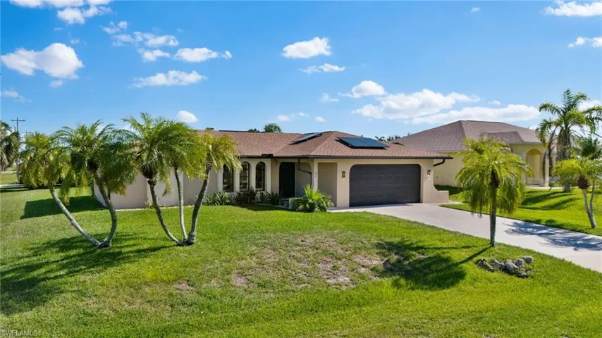 View of front of house featuring a garage, a front yard, and solar panels