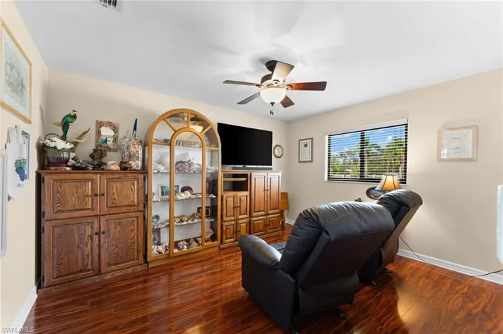 Secondary bedroom being used as a sitting room with ceiling fan and hardwood / wood-style flooring