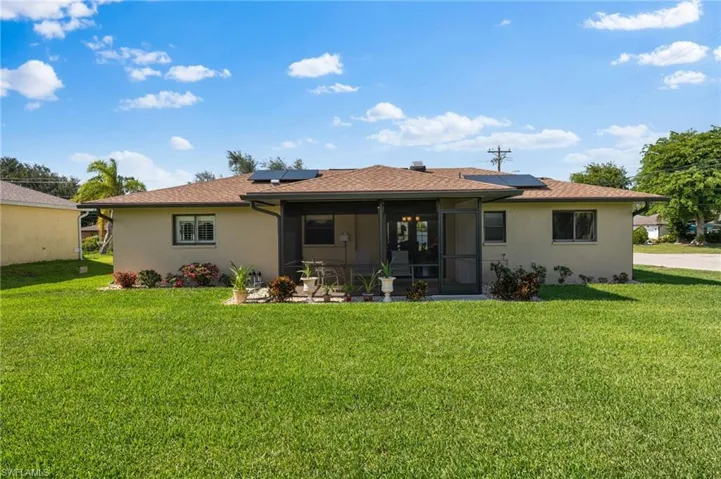Rear view of property featuring a yard and solar panels