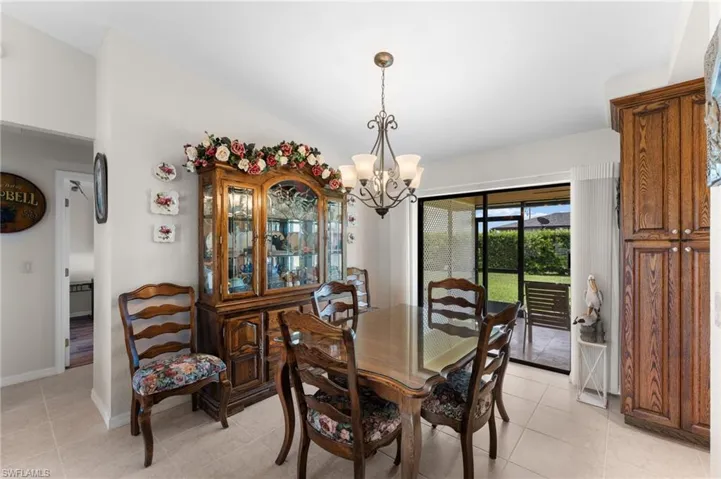Tiled dining room with a chandelier and lofted ceiling