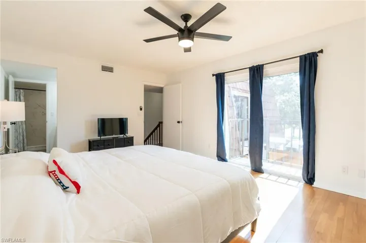 Bedroom featuring access to exterior, wood finished floors, a ceiling fan, and ensuite bathroom