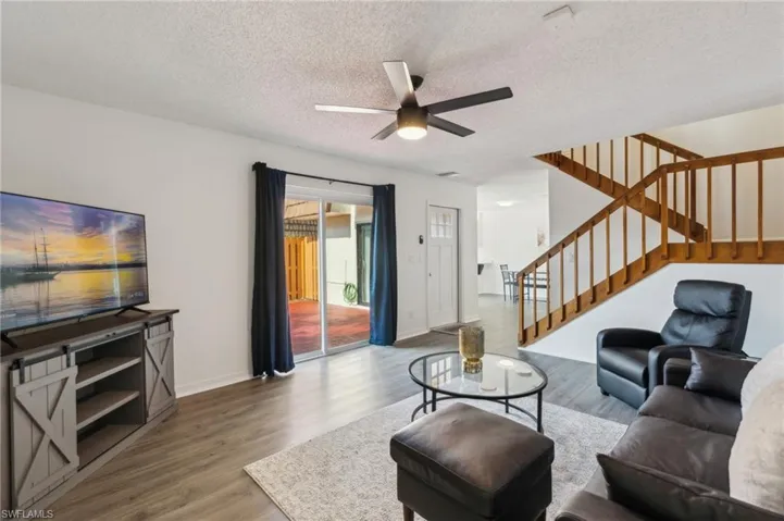 Living room featuring wood finished floors, a textured ceiling, stairs, and ceiling fan