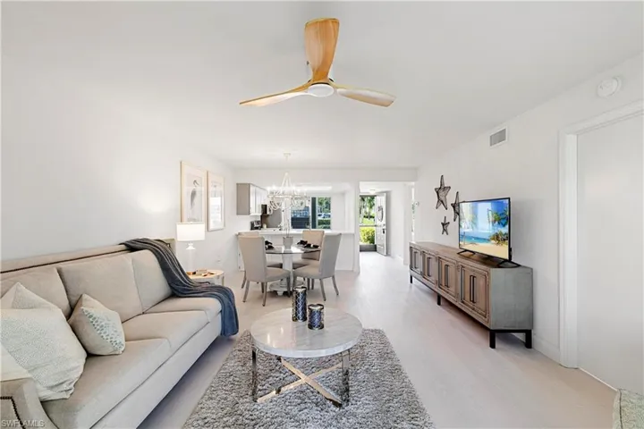 Living room with ceiling fan with notable chandelier and light hardwood / wood-style flooring