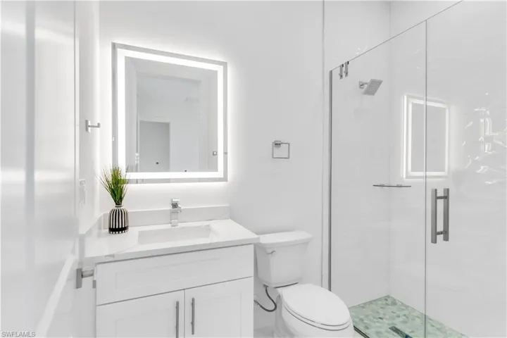 Bathroom with vanity, toilet, and a shower with shower door