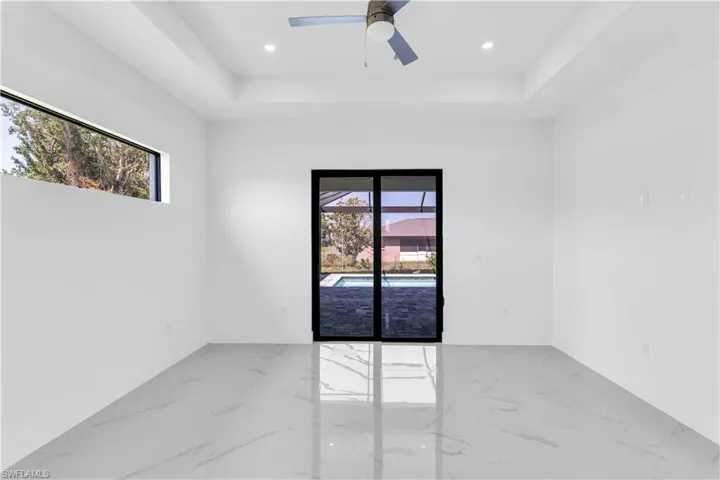 Unfurnished room with a tray ceiling, plenty of natural light, and ceiling fan
