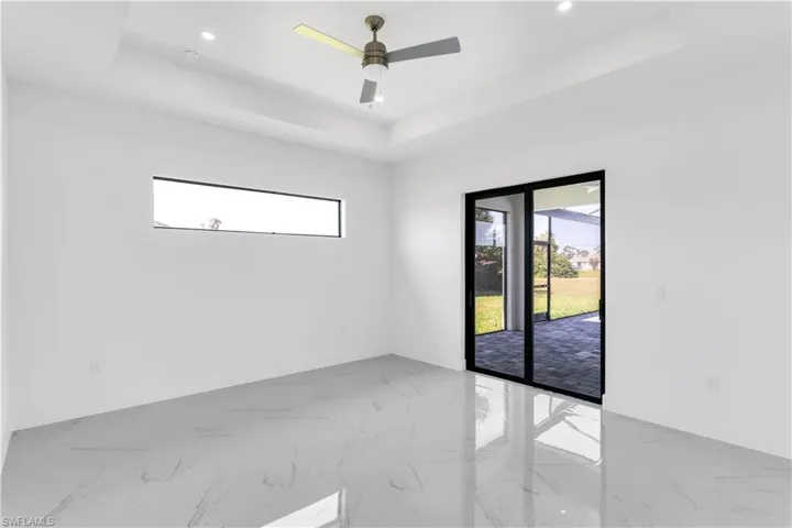 Empty room featuring a tray ceiling, plenty of natural light, and ceiling fan