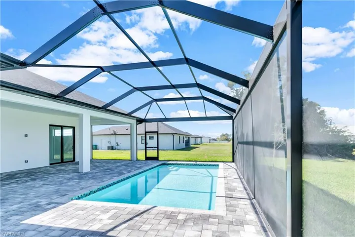View of swimming pool with a patio, glass enclosure, and a lawn