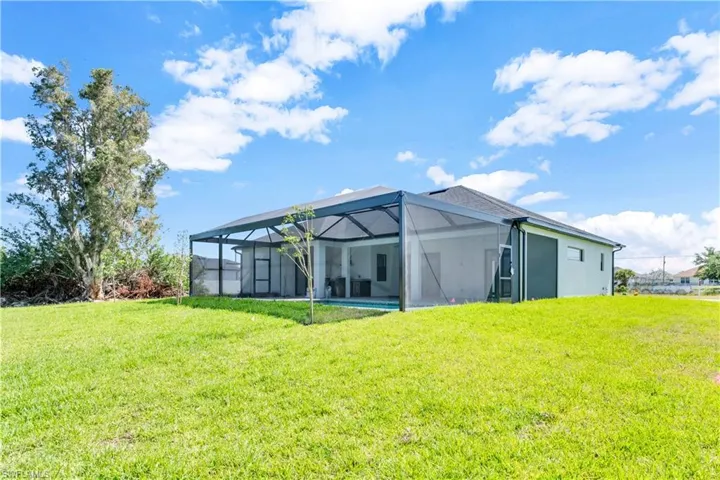 Back of property featuring a yard and glass enclosure