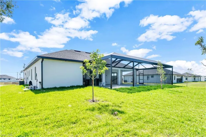 Rear view of house with a lawn and a lanai