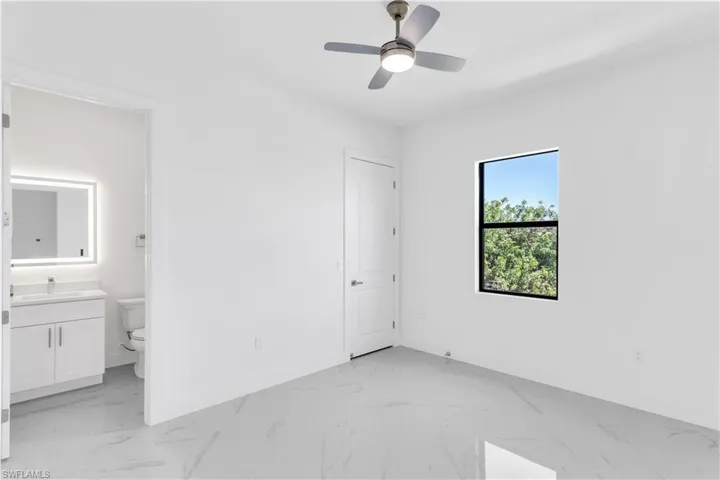 Unfurnished bedroom with connected bathroom, ceiling fan, and sink