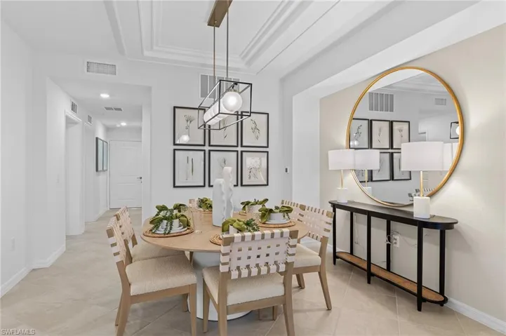 Dining area featuring a tray ceiling, ornamental molding, and light tile patterned flooring