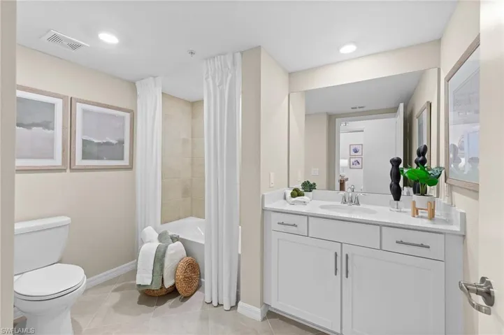 Bathroom featuring light tile patterned floors, vanity, shower / bathtub combination with curtain, and recessed lighting