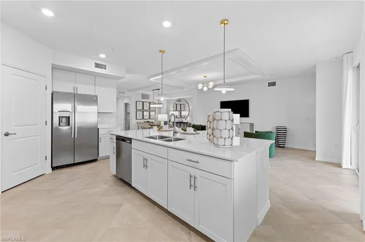 Kitchen with white cabinetry, decorative light fixtures, open floor plan, stainless steel appliances, and light stone counters
