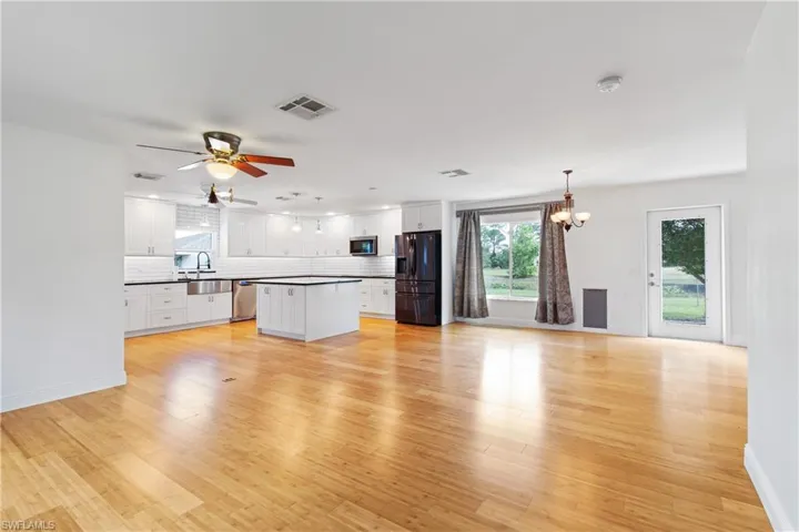 Unfurnished living room with ceiling fan with notable chandelier, light hardwood / wood-style flooring, and sink
