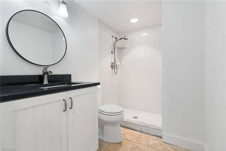 Bathroom with tiled shower, vanity, and toilet