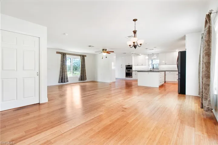 Unfurnished living room featuring light hardwood / wood-style flooring and ceiling fan with notable chandelier