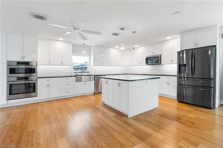 Kitchen featuring white cabinets, sink, hanging light fixtures, and appliances with stainless steel finishes