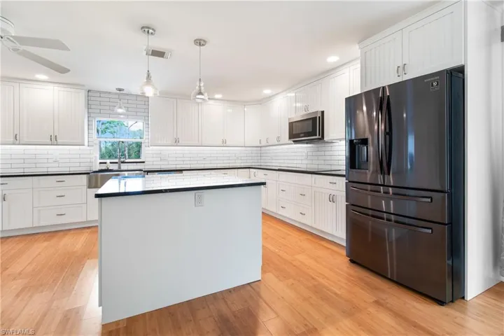 Kitchen with ceiling fan, backsplash, decorative light fixtures, white cabinets, and appliances with stainless steel finishes