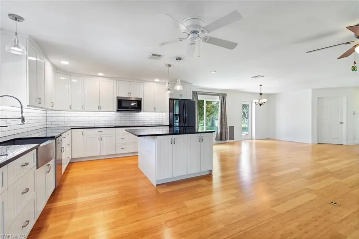 Kitchen with sink, white cabinets, stainless steel appliances, and decorative light fixtures