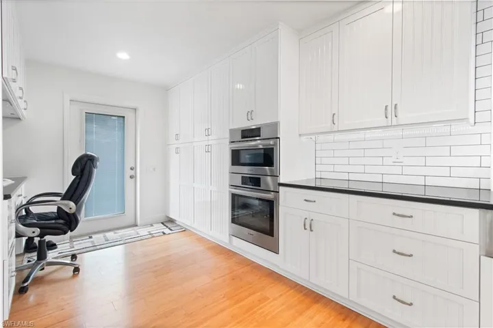 Kitchen with white cabinets, stainless steel double oven, and light wood-type flooring