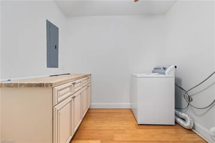 Washroom featuring cabinets, light wood-type flooring, electric panel, and washer / clothes dryer