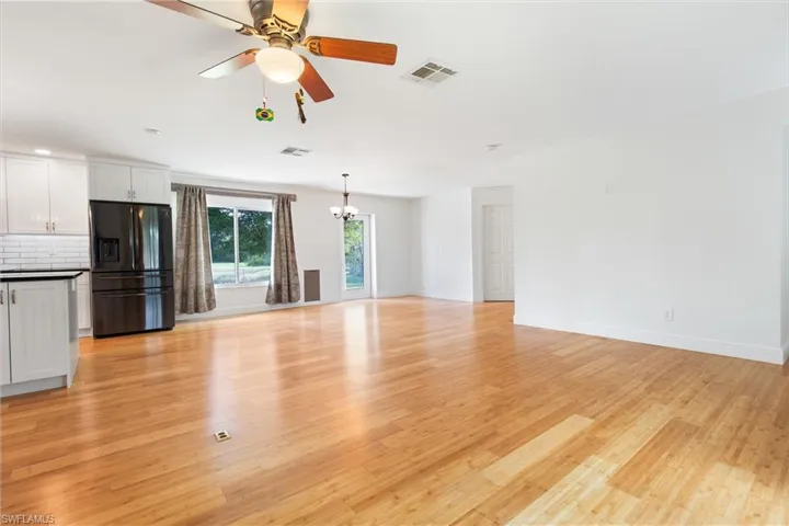 Unfurnished living room with light wood-type flooring and ceiling fan with notable chandelier