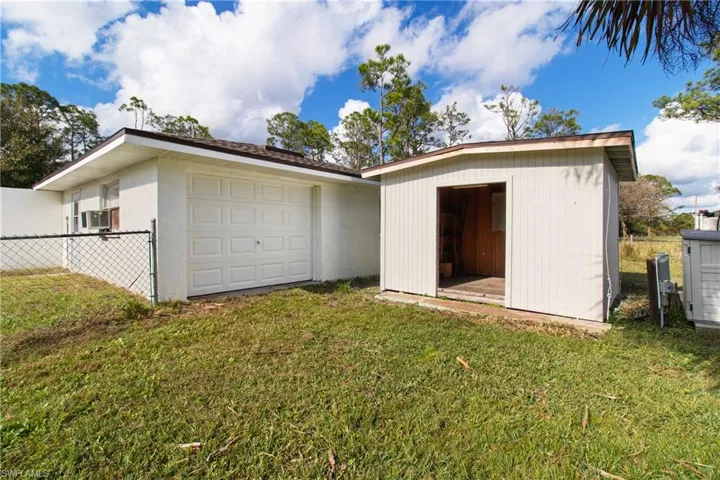 Back of house with cooling unit, an outdoor structure, and a lawn