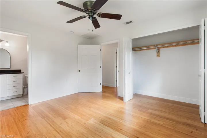 Unfurnished bedroom with ensuite bathroom, a closet, light hardwood / wood-style floors, and ceiling fan