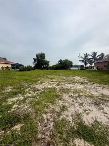 Expansive open lot featuring partial grass coverage and sandy ground