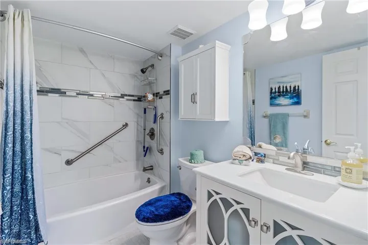 Full bathroom featuring shower / bath combination with curtain, toilet, and vanity