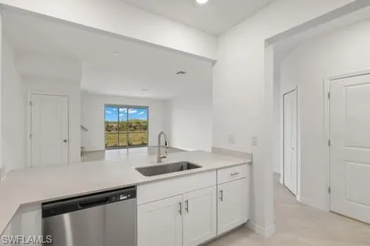 Kitchen featuring stainless steel dishwasher, white cabinetry, light countertops, a peninsula, and recessed lighting