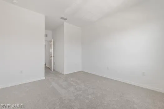 Empty room featuring carpet and lofted ceiling