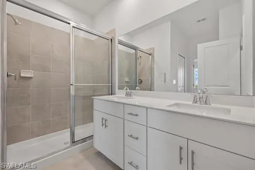 Full bathroom featuring double vanity, a shower stall, and tile patterned floors