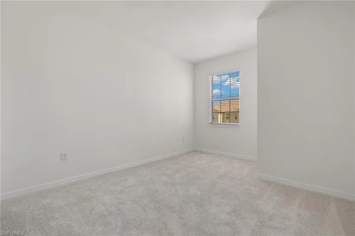 Spare room featuring light colored carpet and baseboards