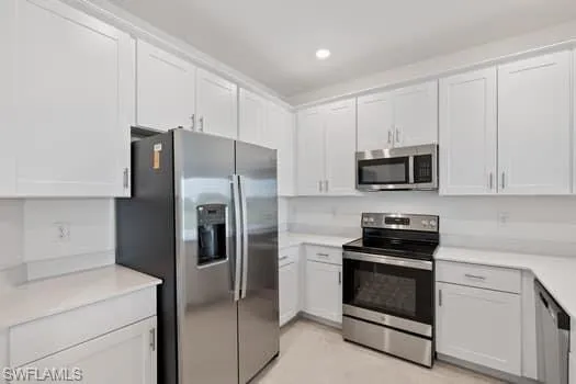 Kitchen featuring stainless steel appliances, white cabinets, light countertops, and recessed lighting
