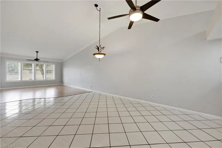 Great room featuring a ceiling fan, vaulted ceiling, and light tile patterned floors