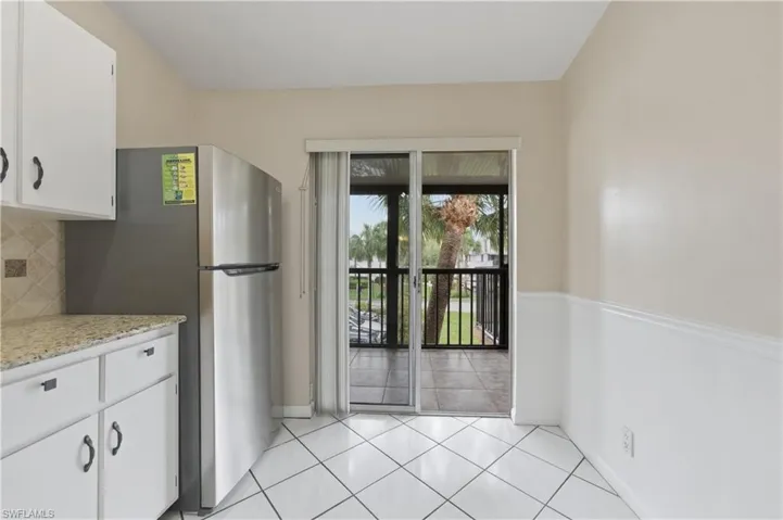 Kitchen featuring white cabinetry, freestanding refrigerator, light tile patterned floors, and backsplash