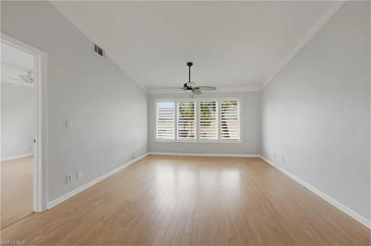 Living room with ceiling fan, light wood finished floors, and crown molding