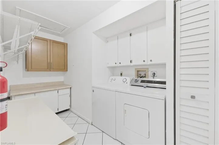 Laundry room with cabinet space, independent washer and dryer, and light tile patterned floors