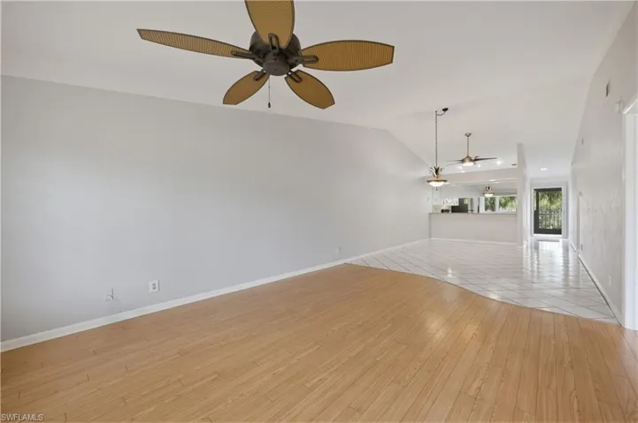 Unfurnished living room featuring light wood finished floors, ceiling fan, and vaulted ceiling