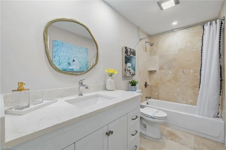 Full bathroom featuring shower / bathtub combination with curtain, vanity, toilet, and tile floors