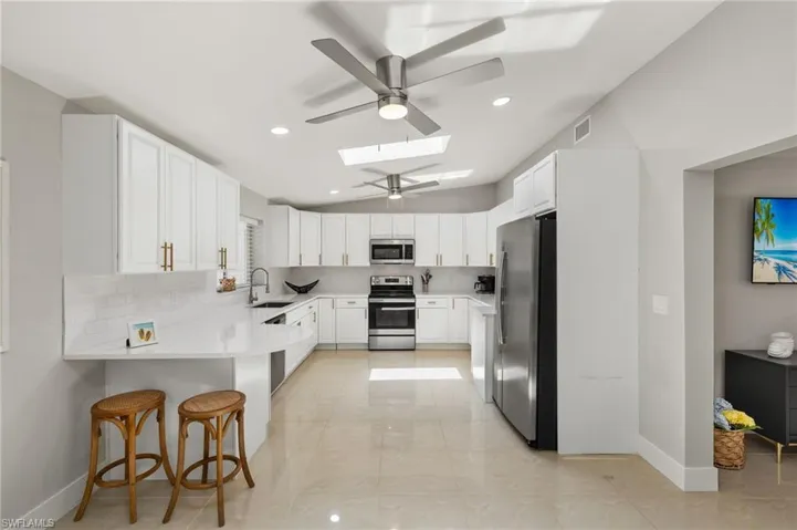 Kitchen featuring appliances with stainless steel finishes, kitchen peninsula, a breakfast bar, sink, and a skylight
