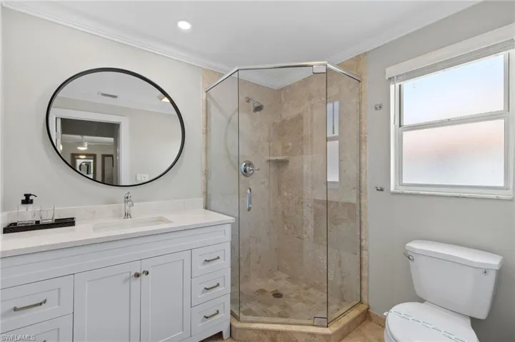 Bathroom with a shower with shower door, crown molding, vanity, and toilet