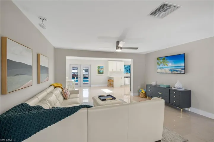 Tiled living room featuring french doors and ceiling fan