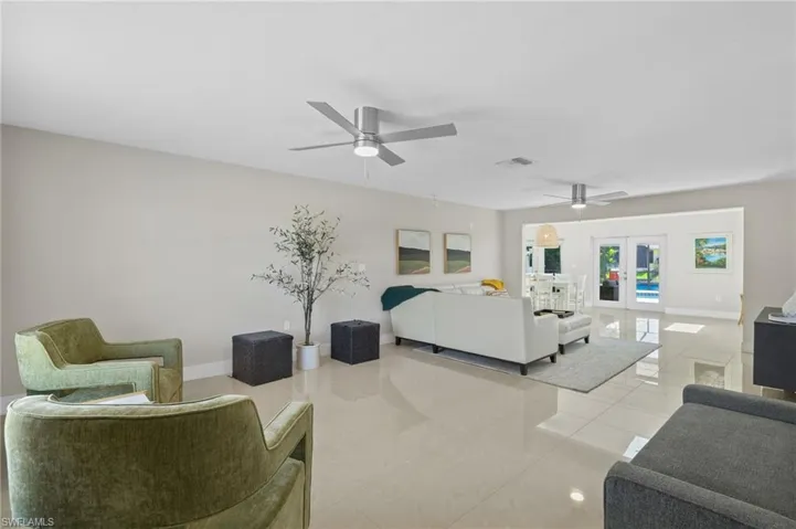Living room with ceiling fan, french doors, and light tile floors