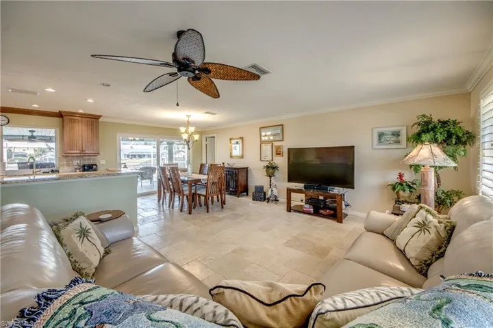 Living area with stone tile floors, crown molding, ceiling fan, and hanging lights